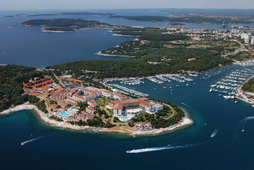 An aerial view of a coastal area with a marina, a resort complex, and surrounding islands. 4