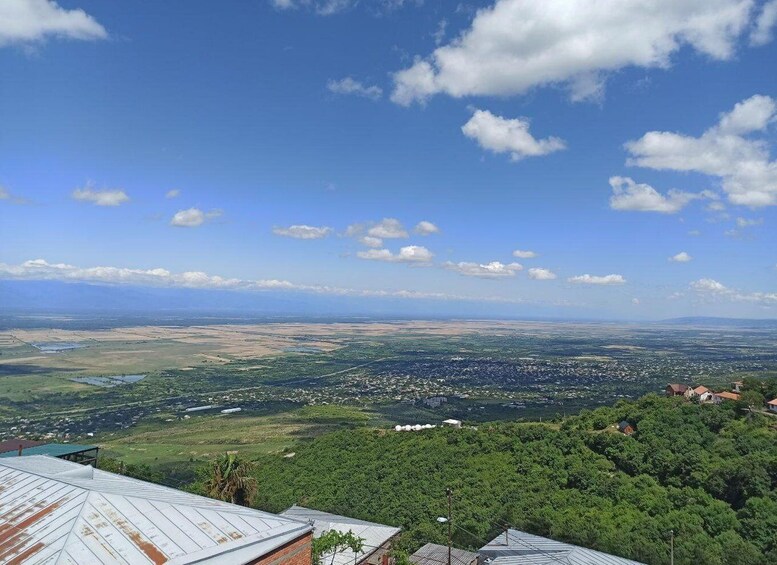 A panoramic view of a landscape with a mix of urban and rural areas, a clear sky, and scattered clouds. 4