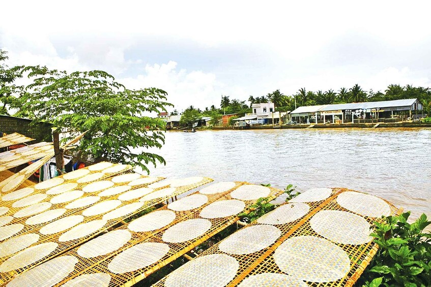 A riverside with floating mats, a boat, and buildings along the shore. 2