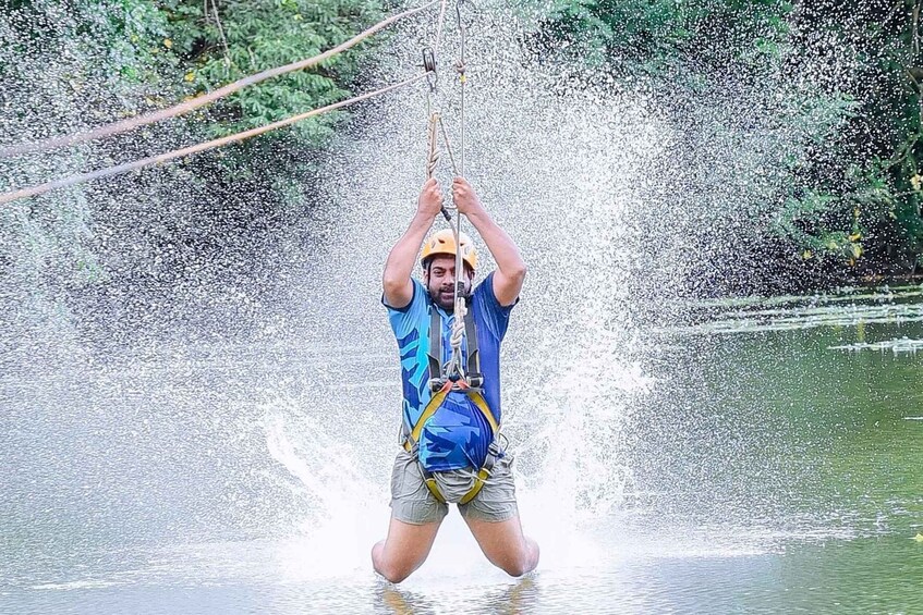 A person zip-lining over water, wearing a helmet and harness. 2