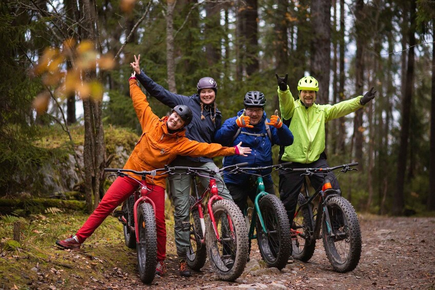 Four people with mountain bikes in a forested area. 3