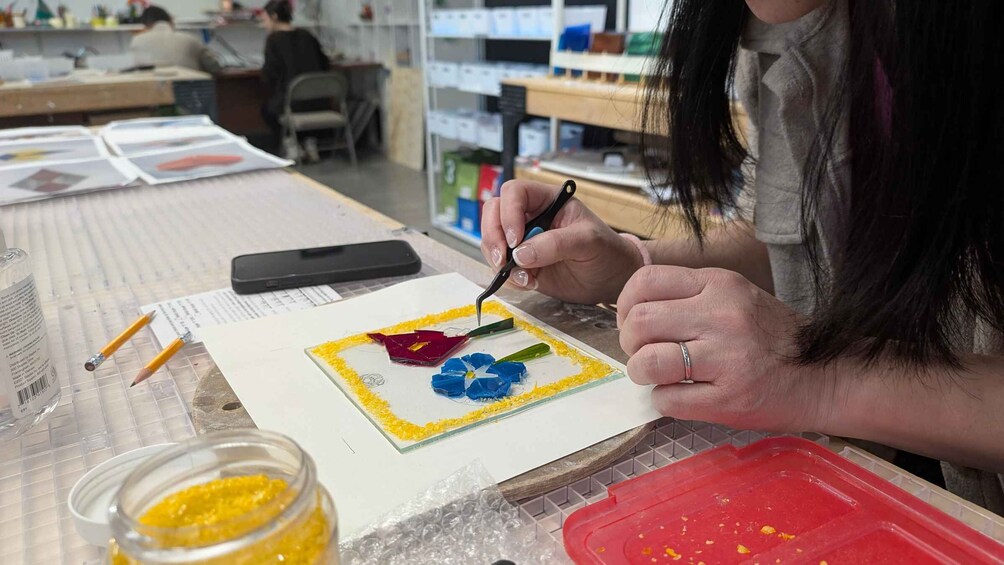 A person painting a flower on paper with a smartphone nearby. 4