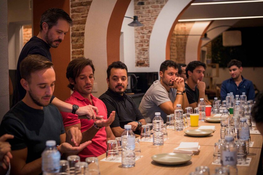 A group of people seated at a long table with water bottles and glasses. 4