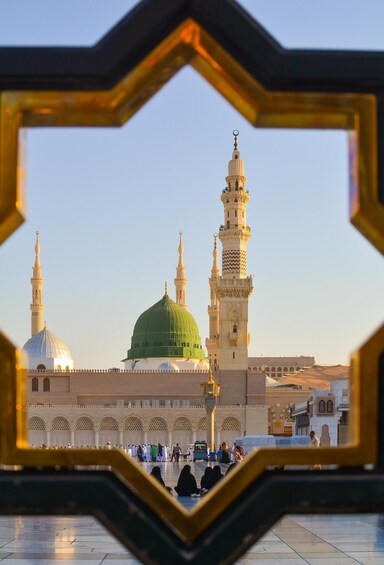 A mosque with a green dome and minarets, viewed through a decorative frame. 1
