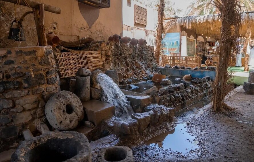 A traditional water feature with a stone cascade, a wooden fence, and a palm tree. 3