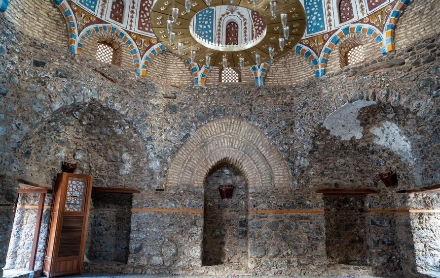 An interior with stone walls, wooden beams, and a decorative ceiling with geometric patterns. 4