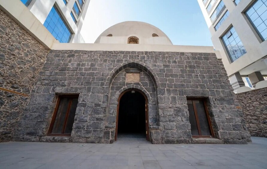 A stone archway leading into a building with a dome and arched windows. 5