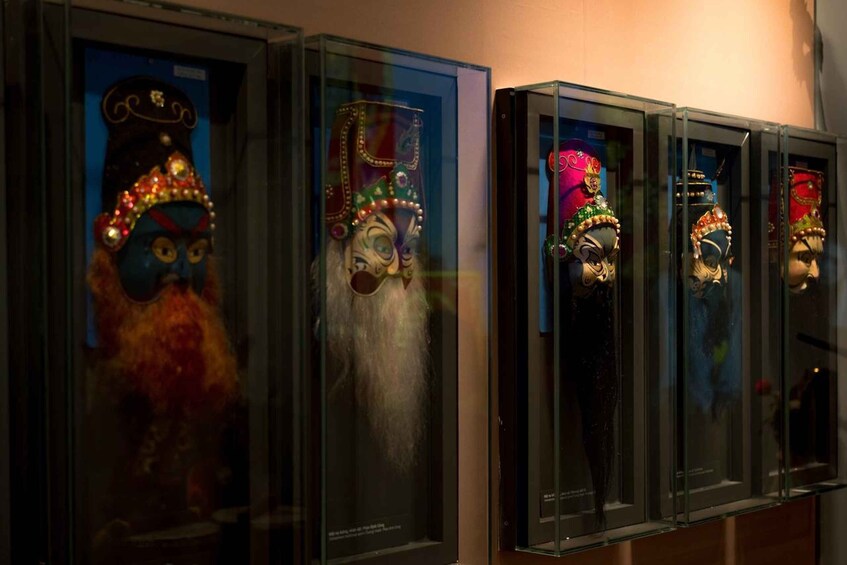 A series of glass display cases containing ornate masks. 4