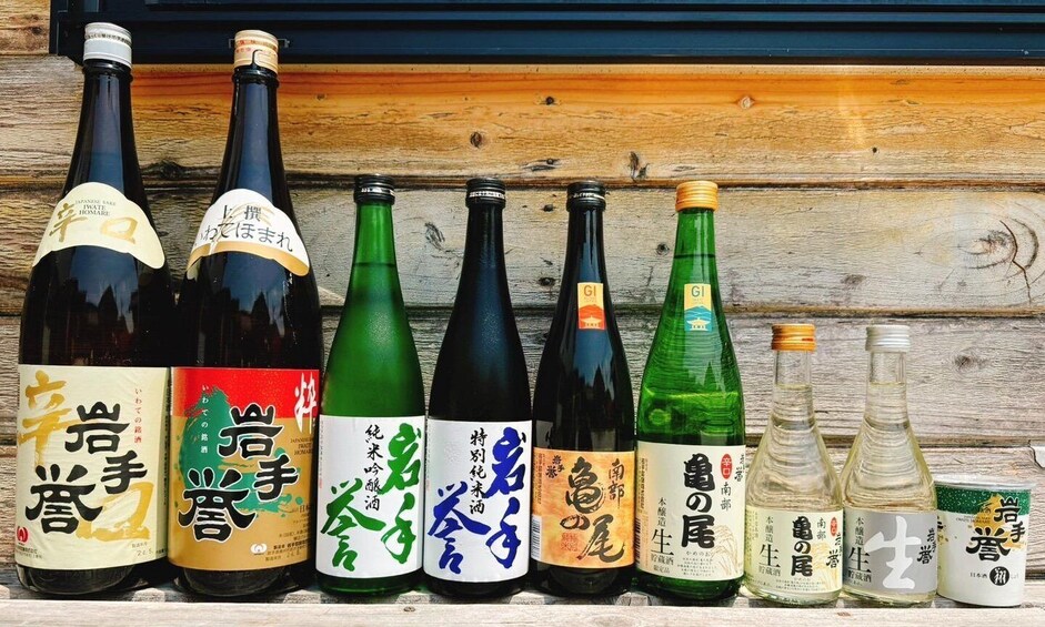 A row of Japanese sake bottles with labels in various colors and scripts. 4