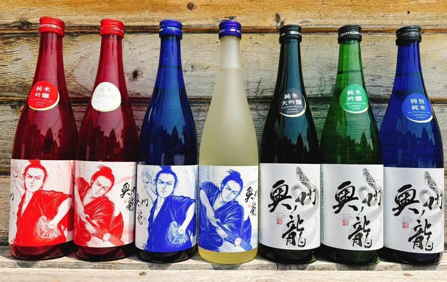 Seven bottles of Junmai sake with different colored labels and artwork. 1