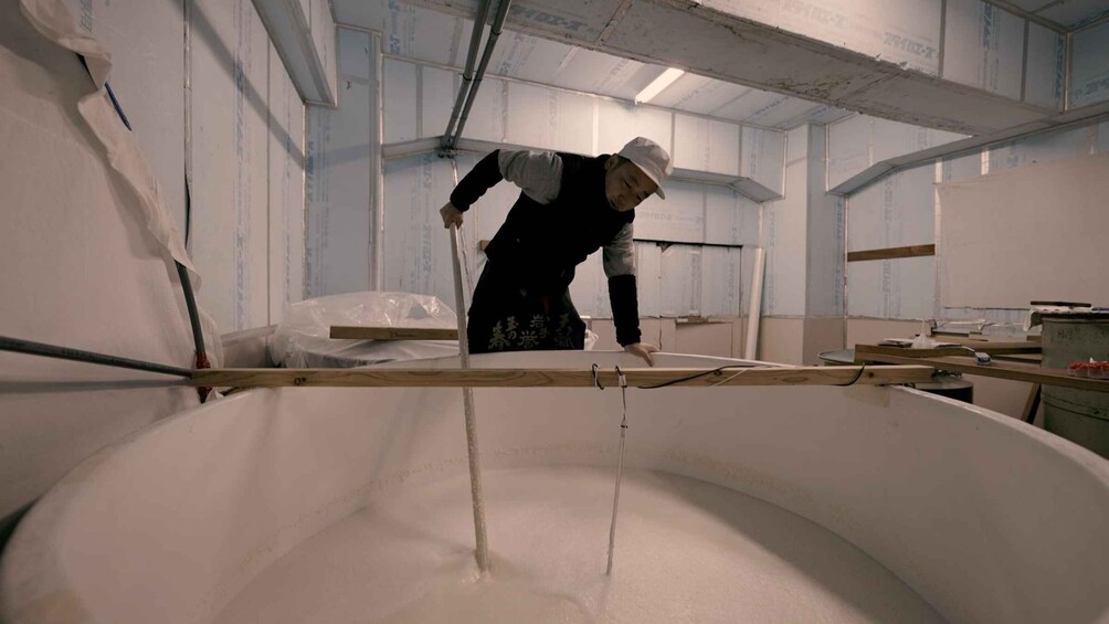 A person working with a large white container in a room with insulation on the walls. 5