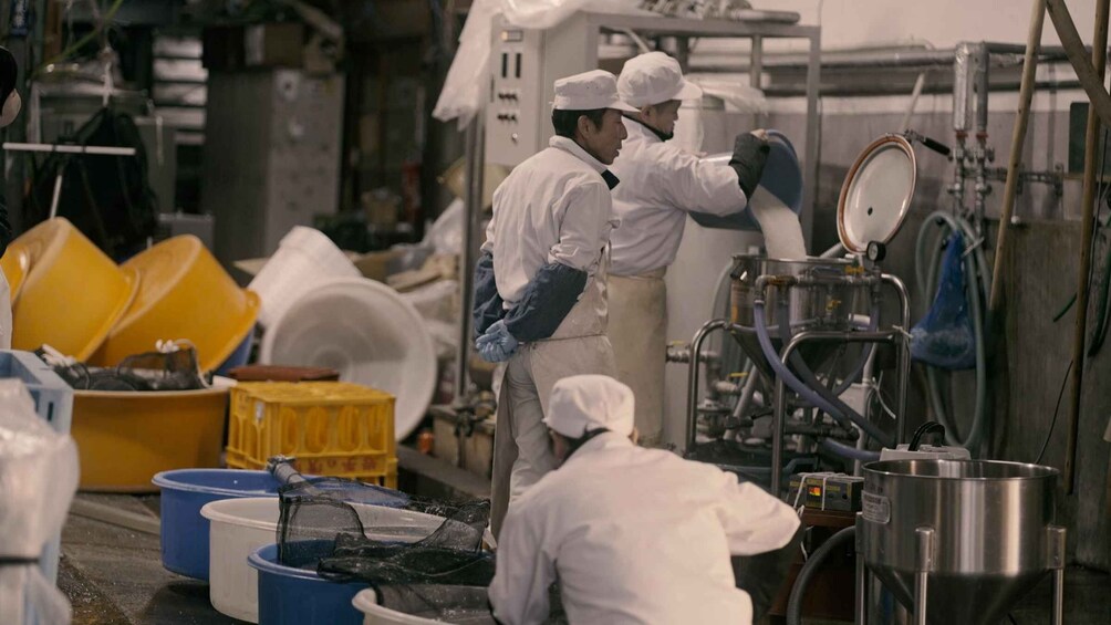 Workers in a kitchen, handling dishes and operating machinery. 2