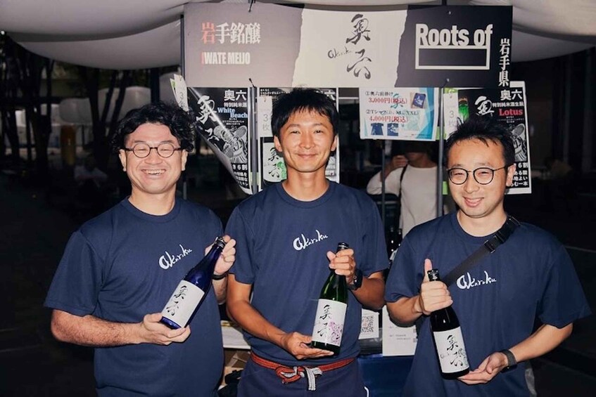Three people wearing 'Akihiko' t-shirts holding bottles. 3