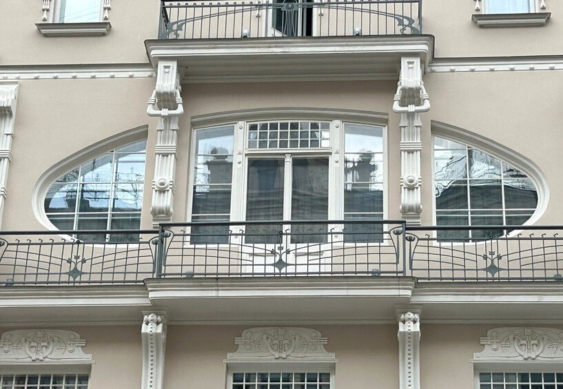 A building with a balcony, ornate window frames, and decorative metal railings. 3