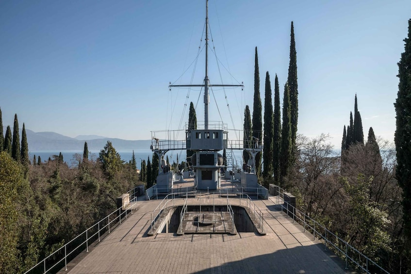 A large ship's mast with a radio antenna, surrounded by trees and a clear sky. 3