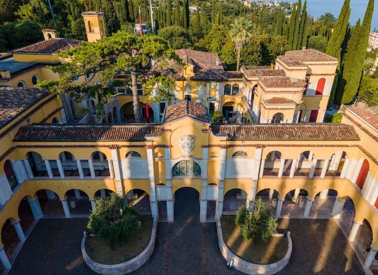 A courtyard with yellow buildings, arches, and trees. 1
