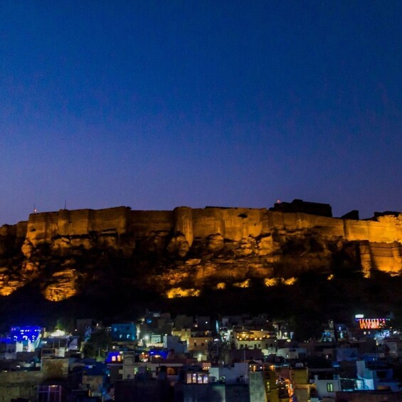 A nighttime view of a city with a prominent cliff and illuminated buildings. 2