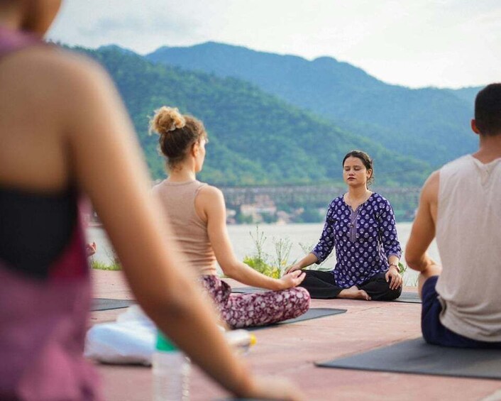A group of people meditating outdoors with a mountainous landscape in the background. 5