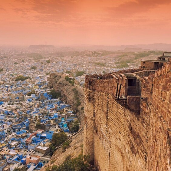 A historic fort overlooking a densely packed town with blue-roofed buildings. 4