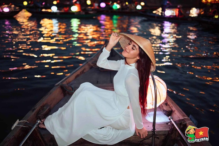 A person in a white dress sitting on a boat at night with reflections on the water. 1