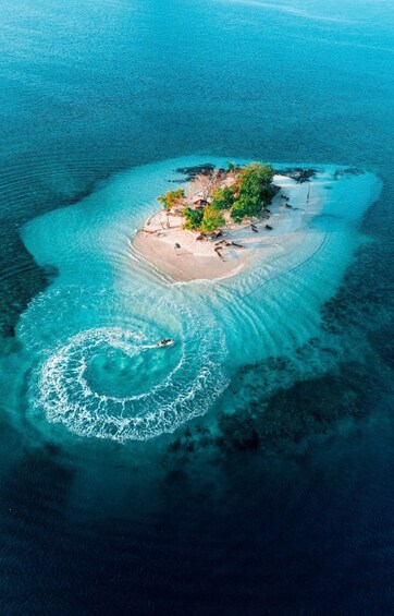 An aerial view of a small island with clear turquoise waters, sandy beaches, and lush vegetation. 3