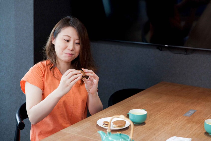 A person sitting at a table with a plate of pancakes, a cup, and a teapot. 2