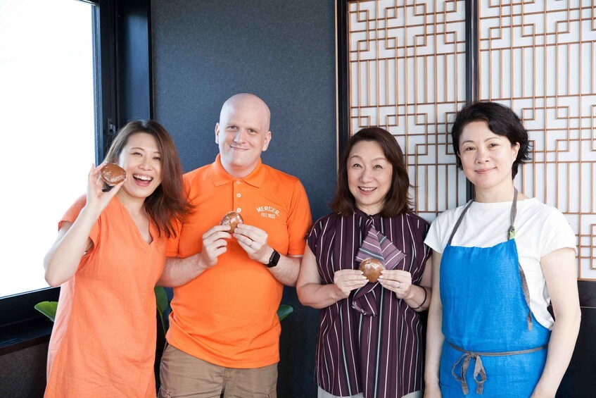 Four people holding donuts in front of a wall with a geometric pattern. 3