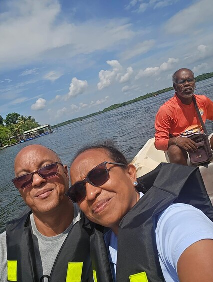 Three people on a boat with a lake and a dock in the background. 2