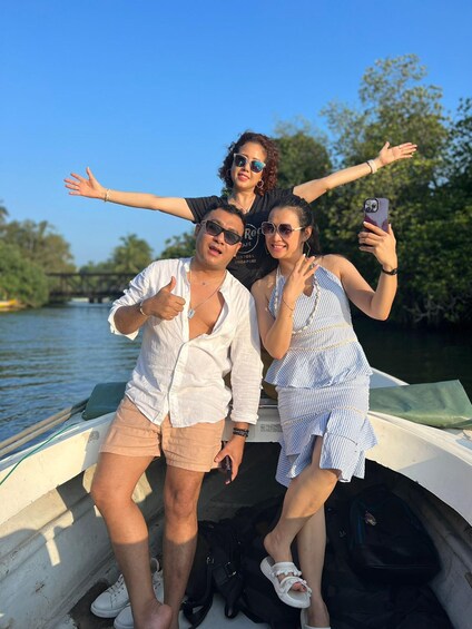 Three people on a boat with water and trees in the background. 1