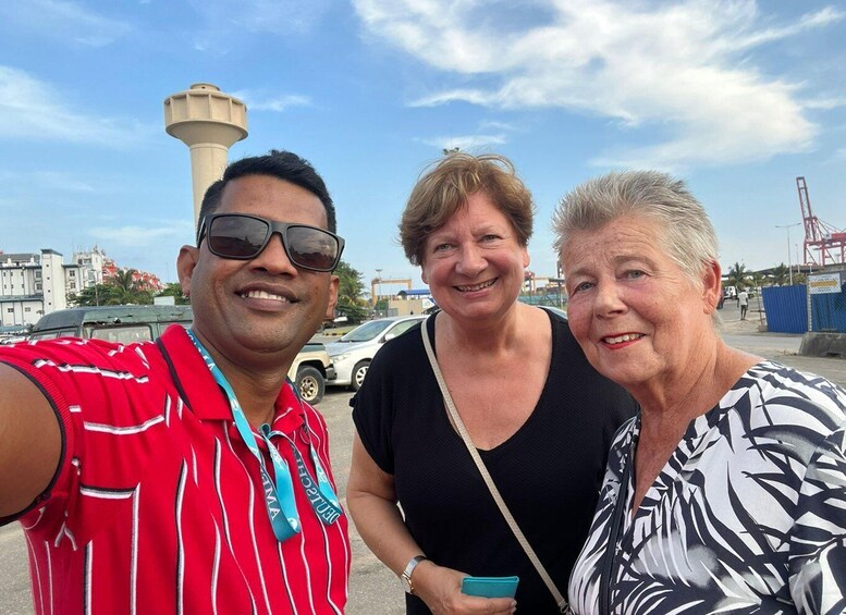 Three people taking a selfie with a lighthouse and industrial structures in the background. 5