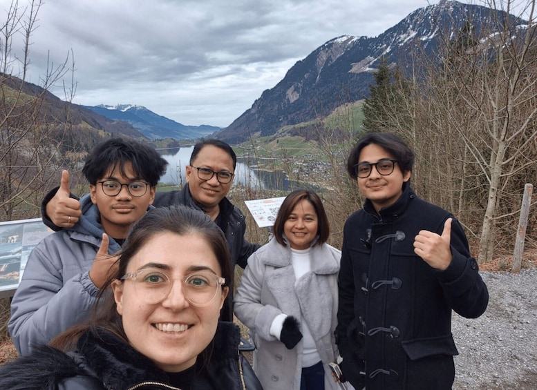 A group of people outdoors with mountains and a river in the background. 2