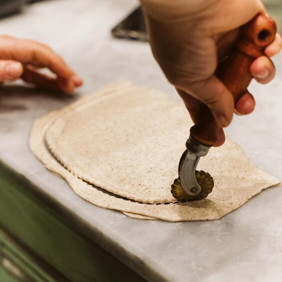 A person using a dough cutter on a flat surface. 1