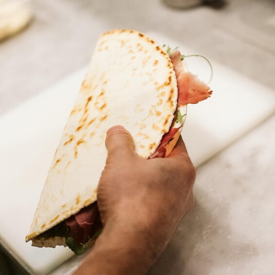 A hand holding a folded tortilla with meat and greens. 4