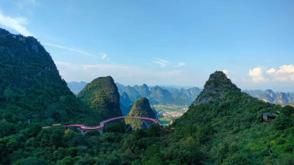 A mountainous landscape with a red bridge and a distant town. 4