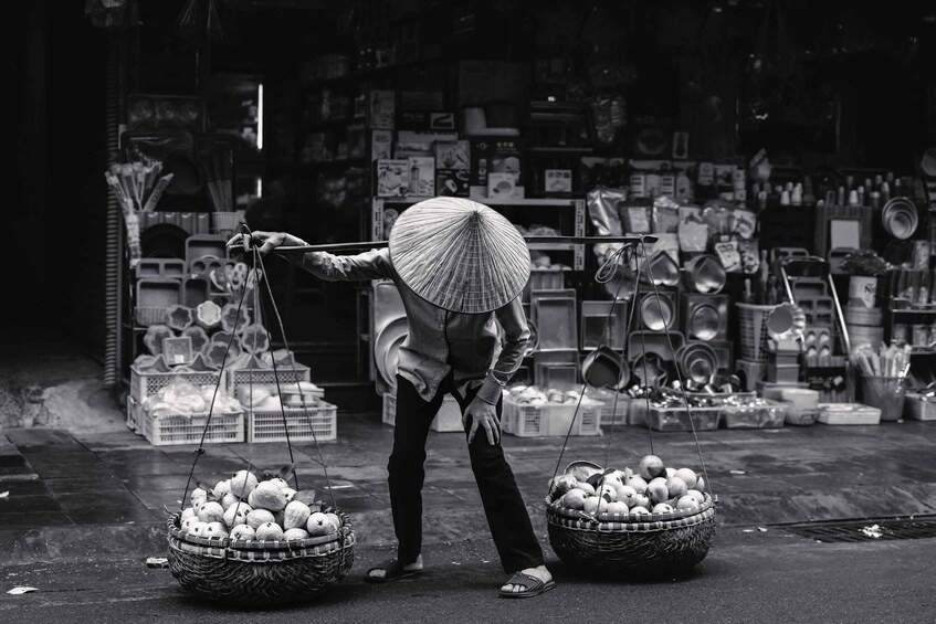 A vendor with a basket of fruits and a parasol. 1
