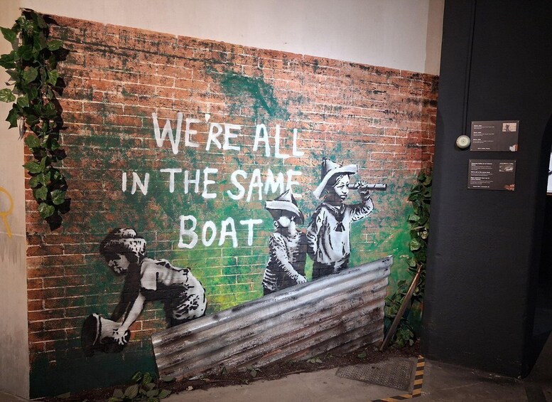 A mural with the text 'WE'RE ALL IN THE SAME BOAT' and two figures, one holding a bat and the other a shovel. 4