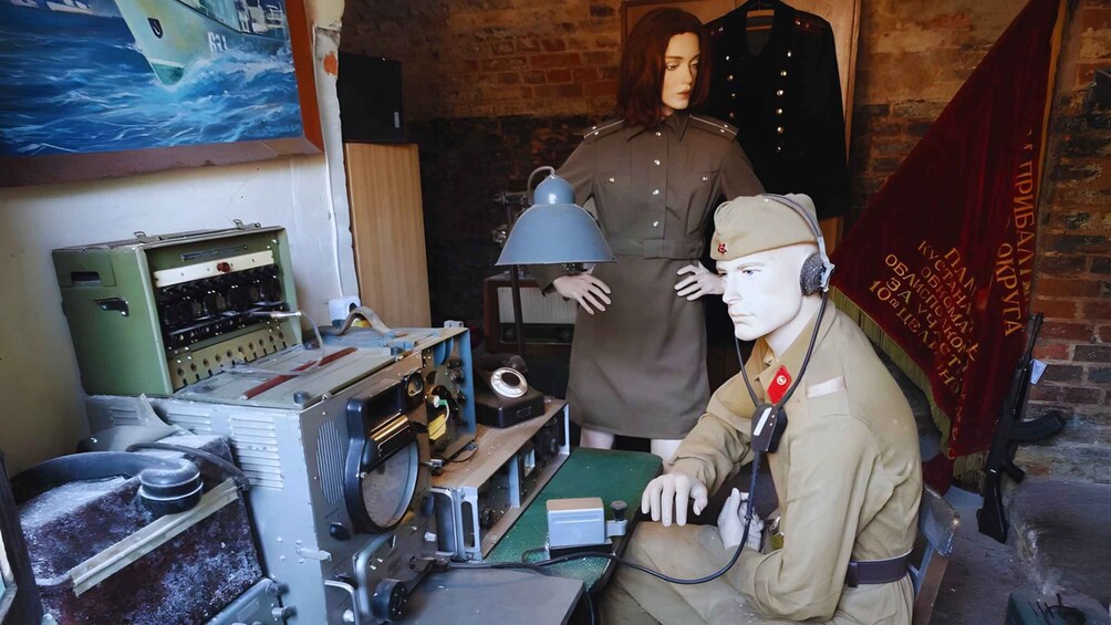 A vintage radio communication setup with a mannequin operator, a brick wall, and a maritime painting. 3