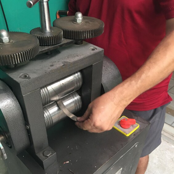A person operating a mechanical press with cylindrical components. 3