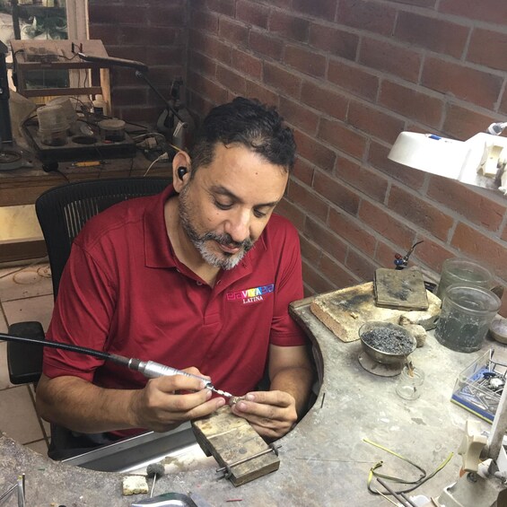A person working with a tool on a metal object in a workshop with brick walls and various tools and materials. 2