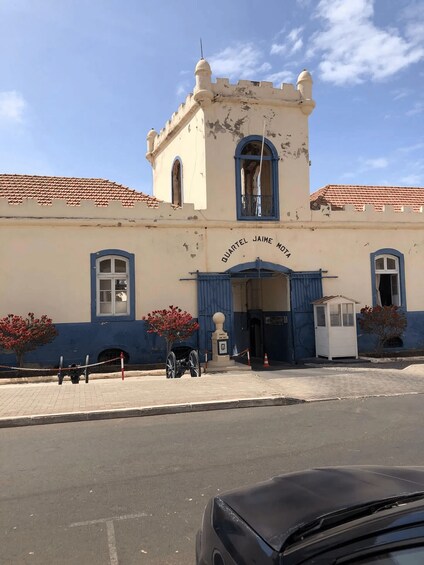 A historic building with a blue and white facade, a turret, and a plaque reading 'QUARTEL JAIME MOTA.' 3