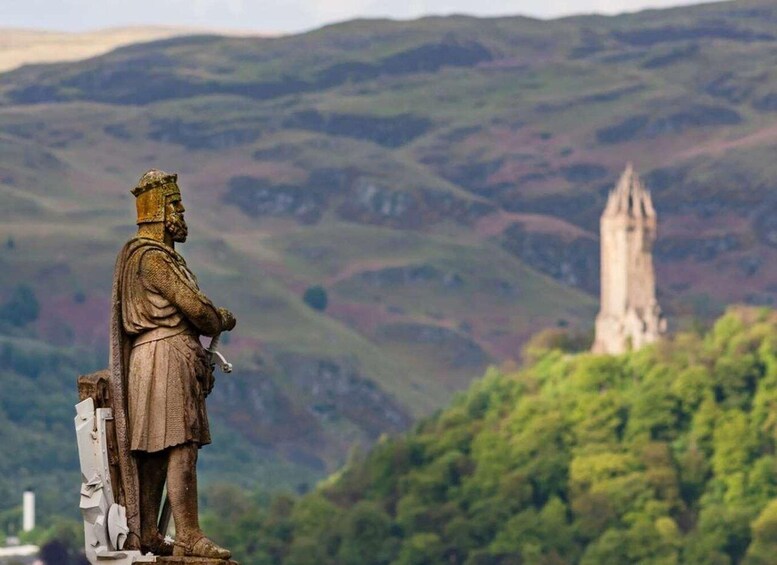 A statue of a historical figure overlooking a hill with a tower in the distance. 3