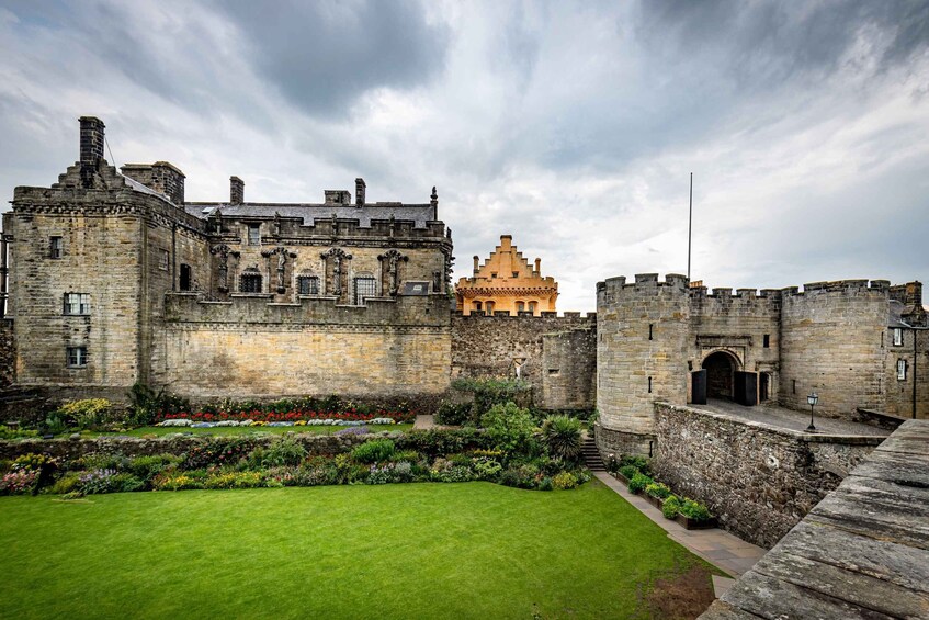 A historic castle with a well-maintained garden and a prominent yellow tower. 2