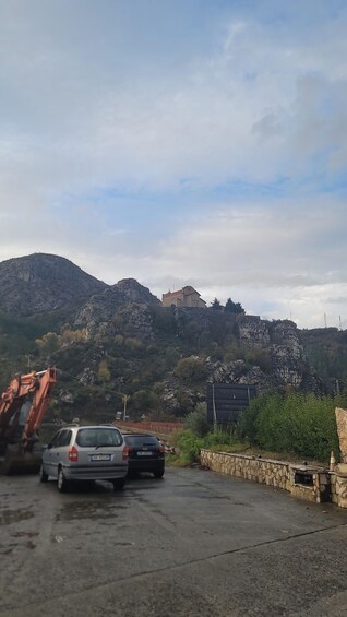 A church on a hill, a parked car, and construction equipment. 1
