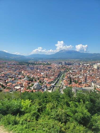 A cityscape with a river running through it, surrounded by mountains and greenery. 5