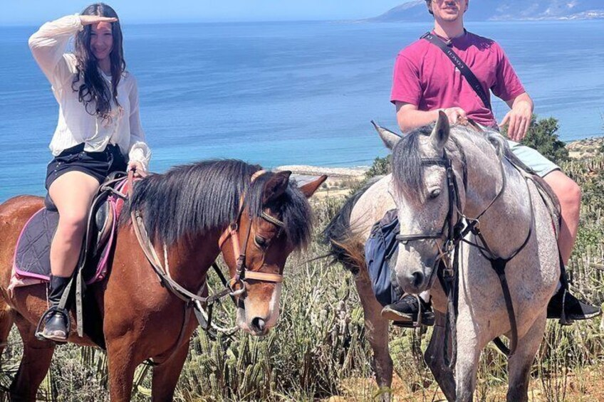 Two people riding horses on a coastal path with the sea in the background. 5