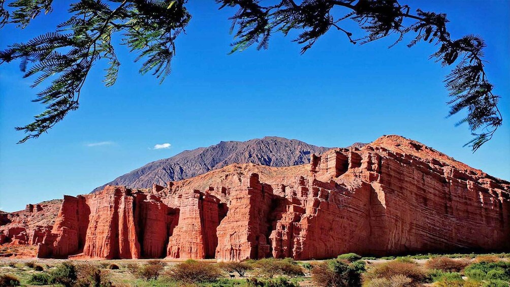 A red rock formation with a mountain in the background. 1