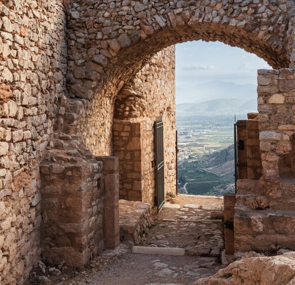 An ancient stone archway leading to a panoramic view of a valley. 2