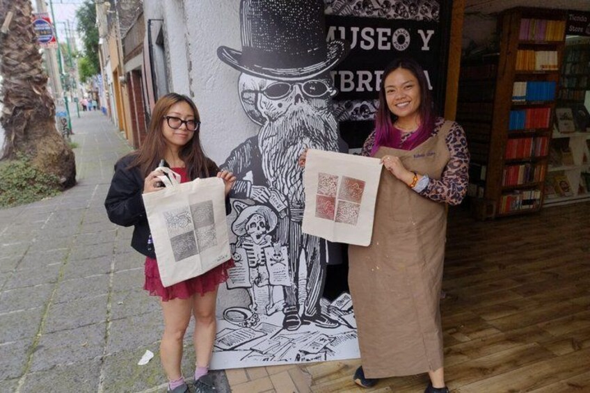 Two people holding shopping bags in front of a bookstore with a mural. 1