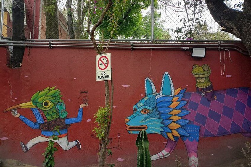 A mural with a bird, a dragon, and a frog on a red wall. 4