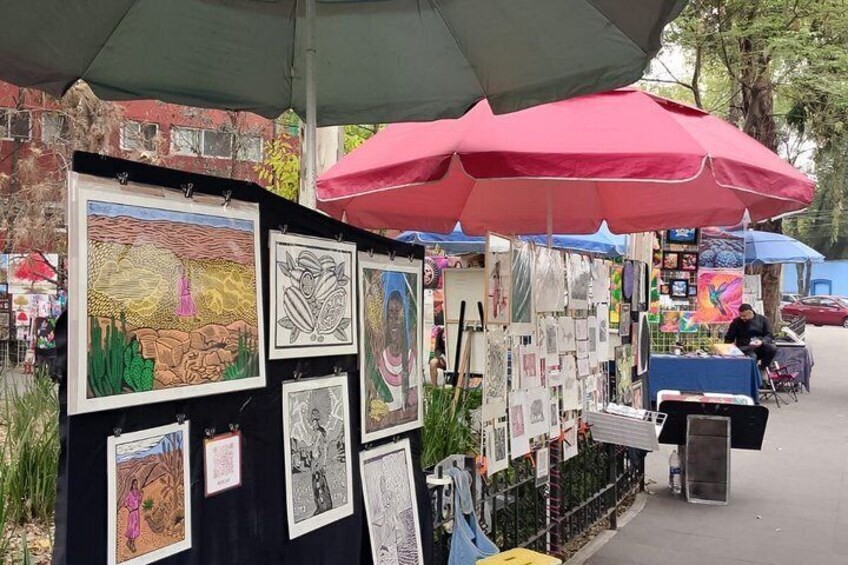 A street art display with various artworks under umbrellas. 4
